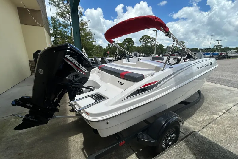 Slide: The Image of 2026 Tahoe T16 boat with Mercury engine, red canopy, parked outdoors on a trailer. - 1