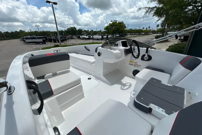 Slide: The Image of 2026 Tahoe T16 boat interior with modern seating and steering, parked outdoors under cloudy skies. - 6