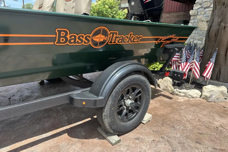 Slide: The Image of 2026 Tracker Bass Tracker Classic Limited boat on trailer with American flags in background. - 2