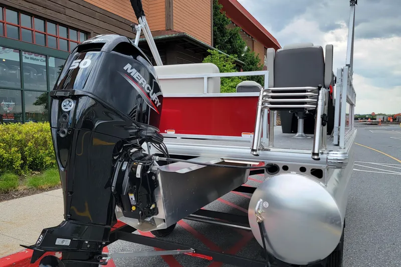 Slide: The Image of 2026 Sun Tracker Bass Buggy 16 XL Select pontoon boat with Mercury 50 engine, parked outdoors. - 2
