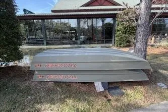 The Image of 2026 Tracker Grizzly 12 Jon boats stacked outdoors near a building. - 0
