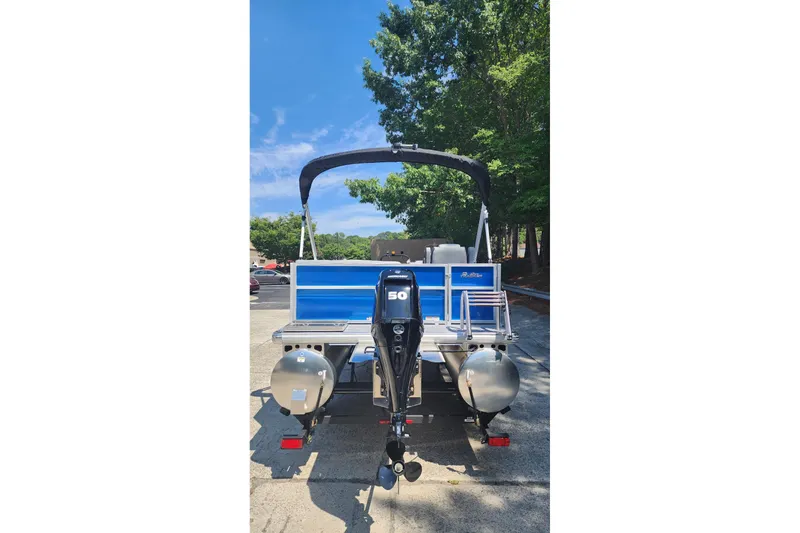 Slide: The Image of 2026 Sun Tracker Party Barge 16 DLX pontoon boat with outboard motor, parked outdoors. - 3