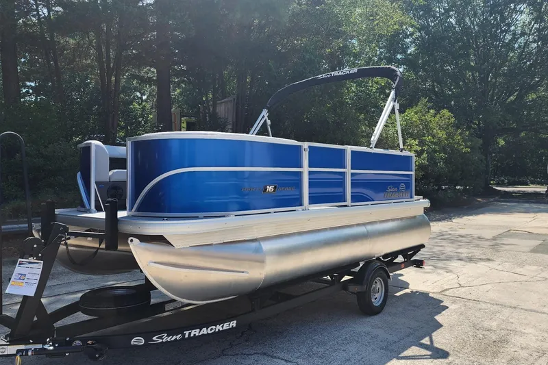 Slide: The Image of 2026 Sun Tracker Party Barge 16 DLX pontoon boat on trailer, parked outdoors. - 1