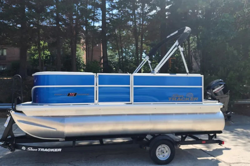 Slide: The Image of 2026 Sun Tracker Party Barge 16 DLX pontoon boat on trailer, parked outdoors. - 65