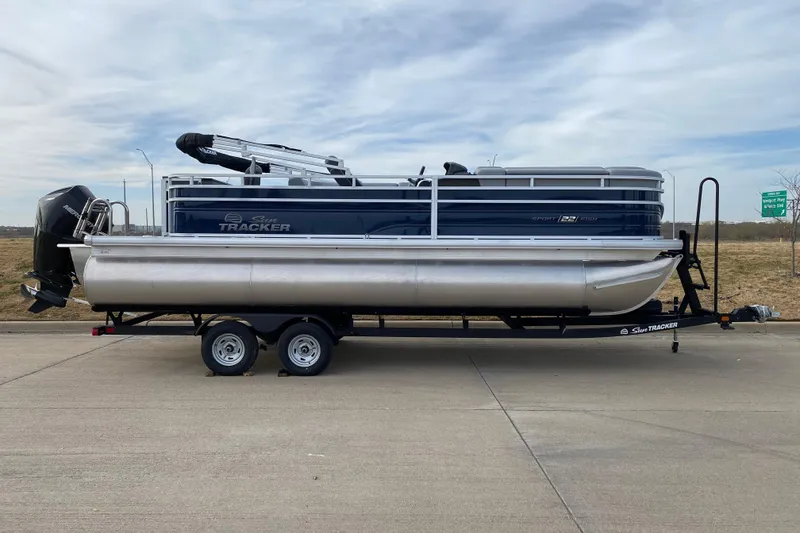 Slide: The Image of 2026 Sun Tracker SportFish 22 XP3 pontoon boat on trailer, parked on roadside. - 1