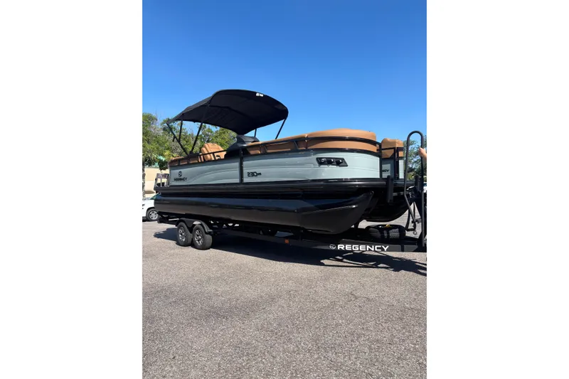 The Image of 2026 Regency 230 DL pontoon boat on trailer, featuring sleek design and canopy. - 0