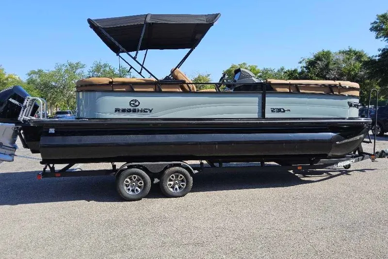 The Image of 2026 Regency 230 DL pontoon boat on trailer, featuring a sleek design and canopy. - 0