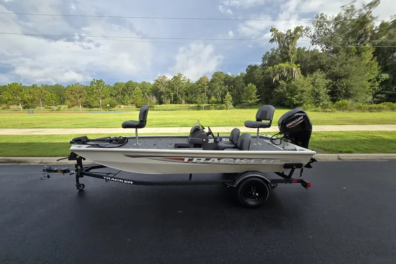 The Image of 2026 Tracker Pro 170 boat on trailer, parked on road with lush greenery background. - 0