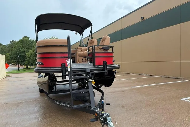 Slide: The Image of 2026 Ranger 220FC pontoon boat with red exterior, parked outdoors on a trailer. - 4