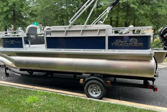 Slide: The Image of 2026 Sun Tracker Bass Buggy 18 DLX pontoon boat on trailer, parked outdoors. - 1