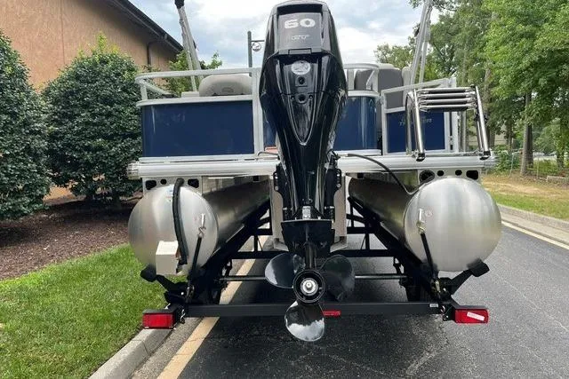 Slide: The Image of 2026 Sun Tracker Bass Buggy 18 DLX pontoon boat with outboard motor, parked on a trailer. - 3