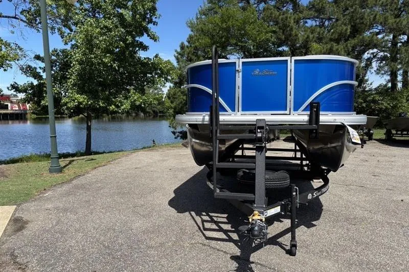 Slide: The Image of 2026 Sun Tracker Party Barge 18 DLX pontoon boat parked by a scenic lake. - 1