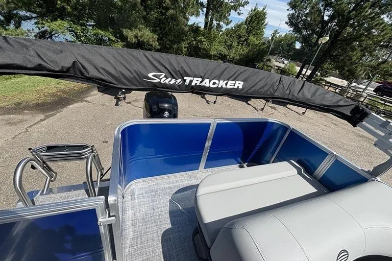 Slide: The Image of 2026 Sun Tracker Party Barge 18 DLX pontoon boat with seating, docked near trees. - 11