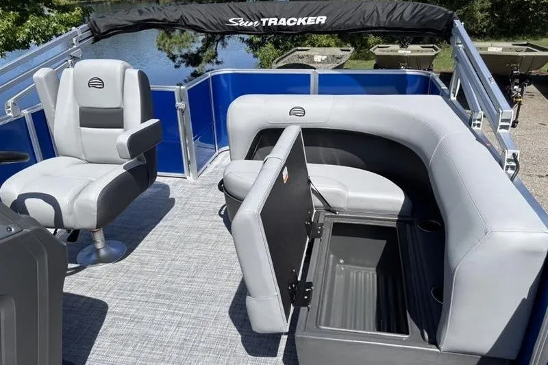 Slide: The Image of 2026 Sun Tracker Party Barge 18 DLX interior with seating and storage, on a sunny day. - 12
