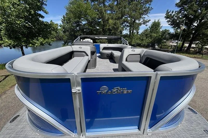 Slide: The Image of 2026 Sun Tracker Party Barge 18 DLX pontoon boat with spacious seating, docked by a scenic lake. - 4