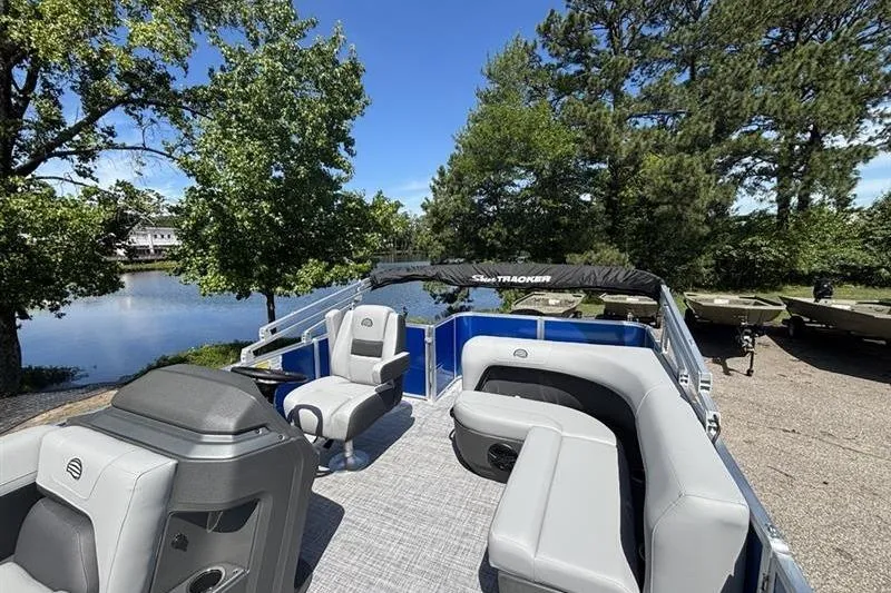 Slide: The Image of 2026 Sun Tracker Party Barge 18 DLX pontoon boat with spacious seating, docked by a scenic lake. - 6