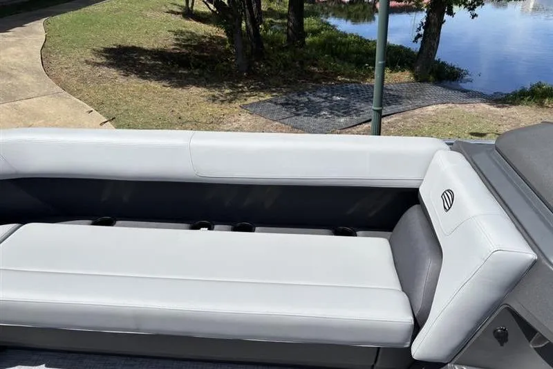 Slide: The Image of 2026 Sun Tracker Party Barge 18 DLX interior seating by a lakeside. - 9