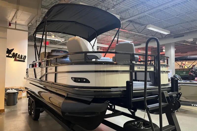 Slide: The Image of 2026 Ranger 220F pontoon boat displayed indoors with canopy and trailer. - 1
