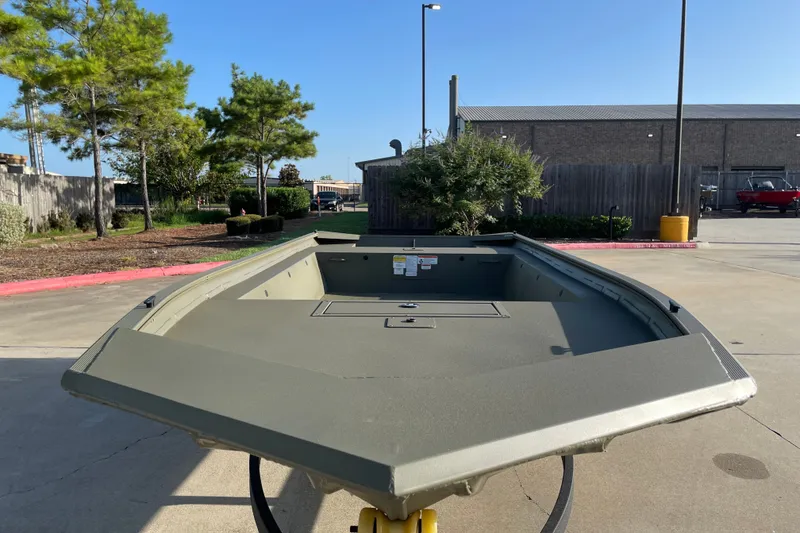 Slide: The Image of 2026 Tracker Grizzly 1754 Utility boat in a parking lot, surrounded by trees and buildings. - 2