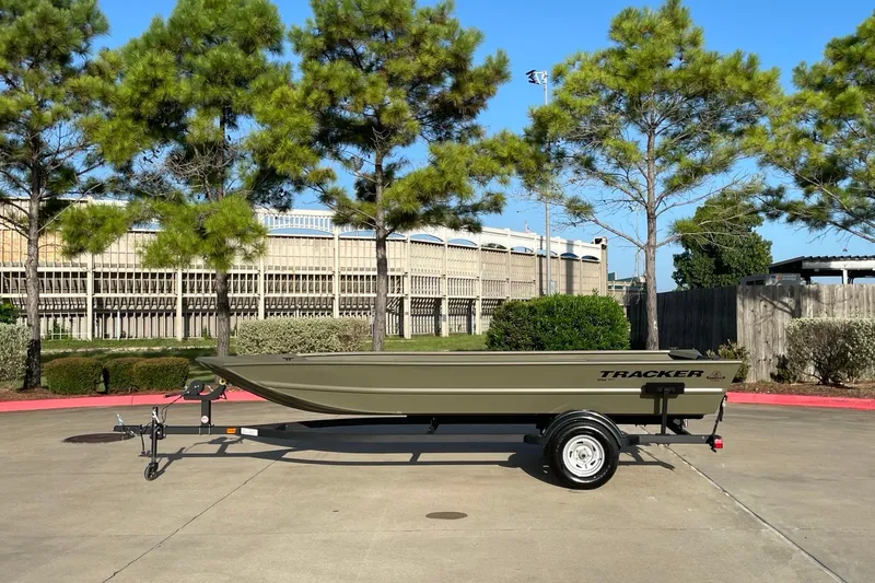 The Image of 2026 Tracker Grizzly 1754 Utility boat on trailer, parked outdoors near trees. - 0