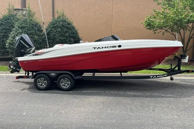 The Image of 2026 Tahoe T21 boat in red and white on a trailer, parked outdoors. - 0