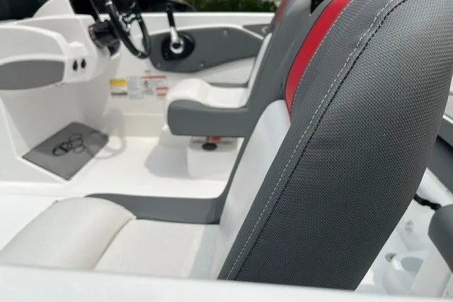 Slide: The Image of 2026 Tahoe T21 boat interior with gray and red seating, steering wheel visible. - 10