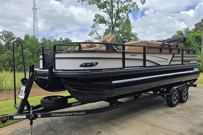 Slide: The Image of 2026 Ranger 220F pontoon boat on trailer, parked outdoors with lush greenery background. - 3