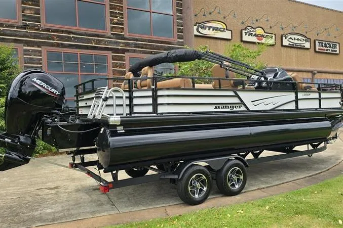 Slide: The Image of 2026 Ranger 220F pontoon boat on trailer, parked outside dealership. - 9