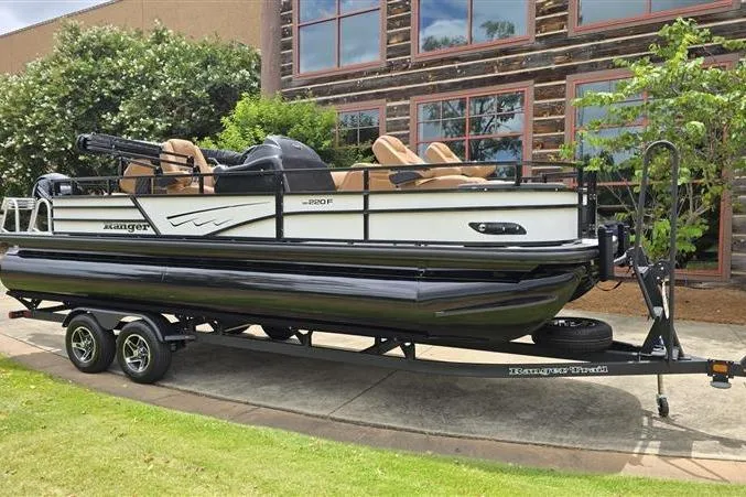 Slide: The Image of 2026 Ranger 220F pontoon boat on trailer, parked outdoors near a building. - 7