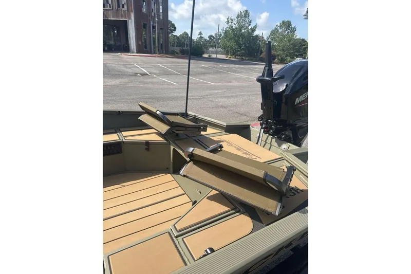 Slide: The Image of 2026 Tracker Grizzly 1756 T Marsh boat interior with seating and motor in a parking lot. - 6