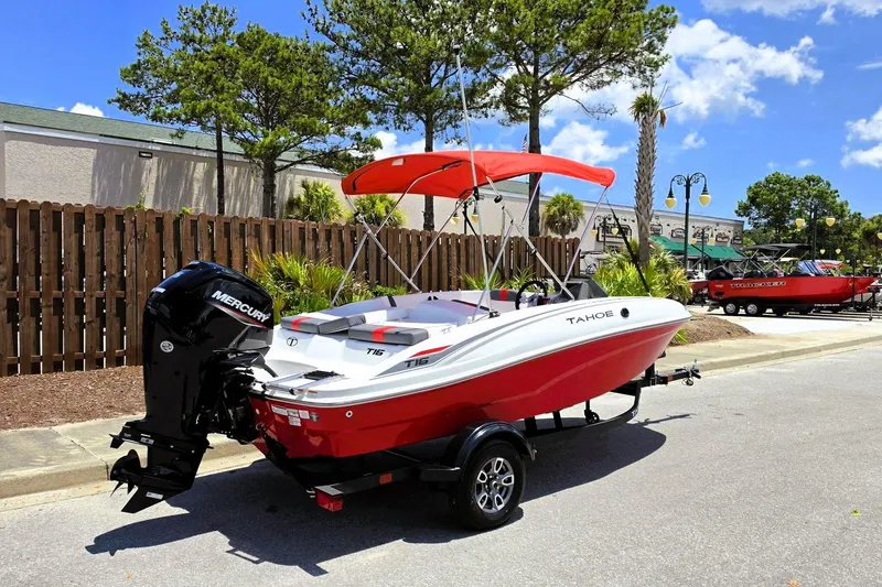 Slide: The Image of 2026 Tahoe T16 boat with Mercury engine, red and white design, parked outdoors. - 2