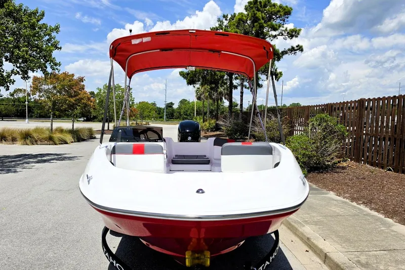Slide: The Image of 2026 Tahoe T16 boat with red canopy, parked outdoors on a sunny day. - 6