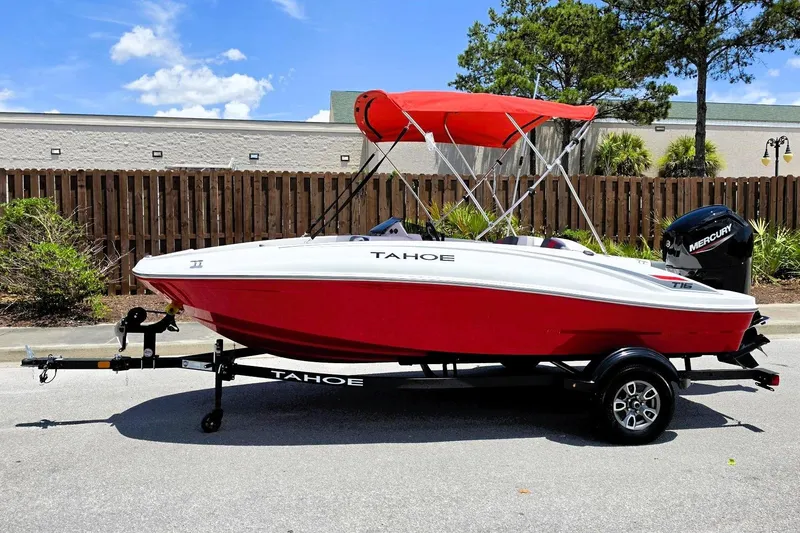 Slide: The Image of 2026 Tahoe T16 boat with red hull and canopy on trailer, parked outdoors. - 7