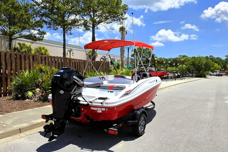 Slide: The Image of 2026 Tahoe T16 boat with red canopy on trailer, parked outdoors. - 3