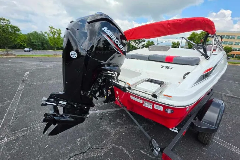 Slide: The Image of 2026 Tahoe T16 boat with Mercury outboard motor, red and white design, parked outdoors. - 2