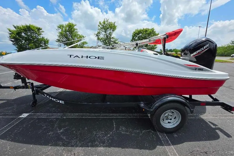 Slide: The Image of 2026 Tahoe T16 boat with red and white design, parked on a trailer under a cloudy sky. - 5