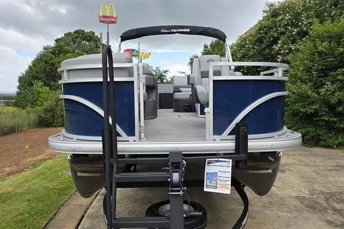 Slide: The Image of 2026 Sun Tracker SportFish 20 DLX pontoon boat on trailer, parked outdoors. - 2
