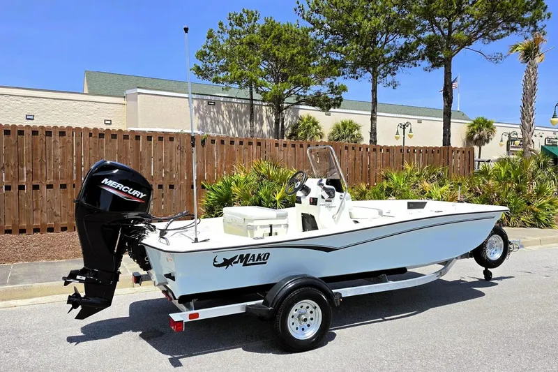 Slide: The Image of 2026 Mako Pro Skiff 15 CC boat with Mercury engine on trailer, parked outdoors. - 1