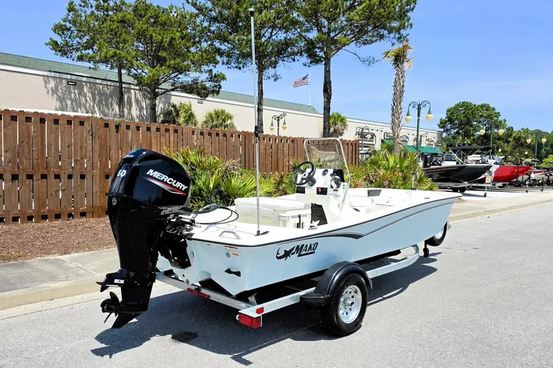 Slide: The Image of 2026 Mako Pro Skiff 15 CC boat with Mercury engine on trailer, parked outdoors. - 2