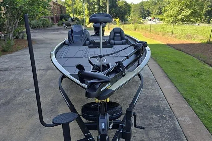 Slide: The Image of 2026 Tracker Savage 215 fishing boat on trailer, parked on driveway with lush greenery. - 6