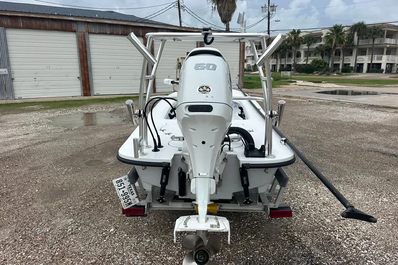 Slide: The Image of 2024 Ankona Advent boat with outboard motor, parked on gravel near garages. - 2