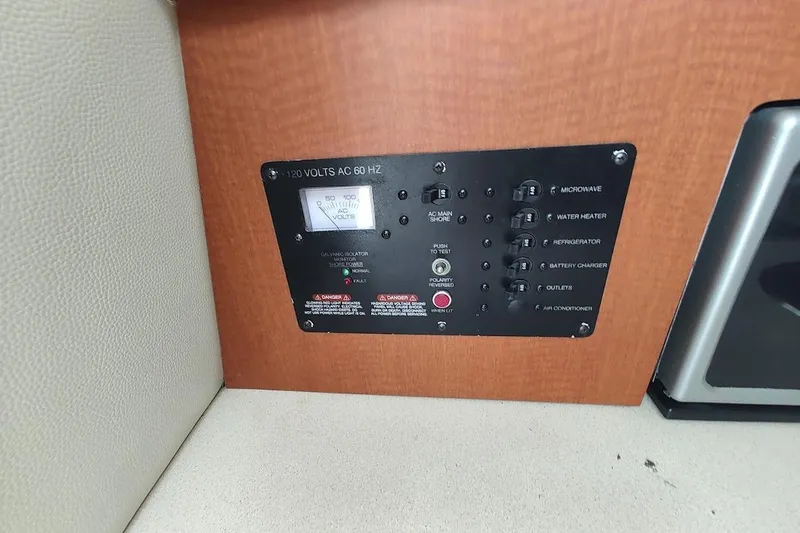 Slide: The Image of Electrical panel on a 2005 Robalo R265 Walkaround boat, featuring various switches and a voltmeter. - 22