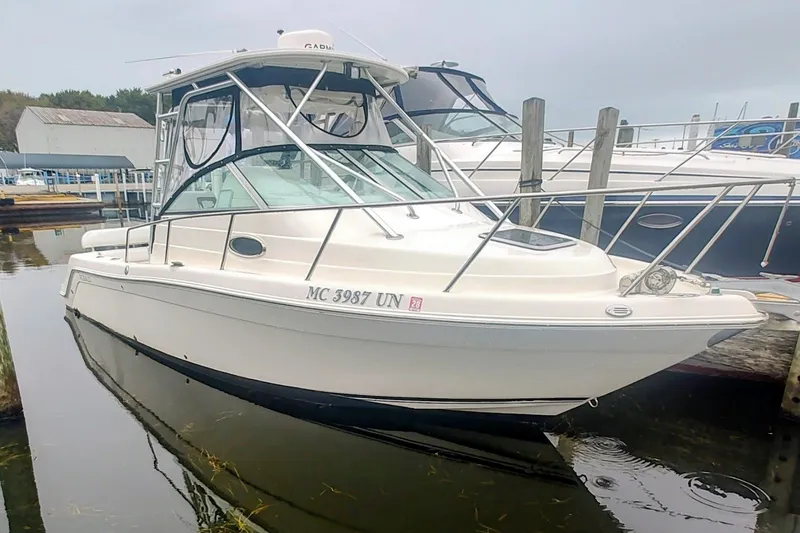 Slide: The Image of 2005 Robalo R265 Walkaround boat docked in a marina, featuring a sleek white design. - 9