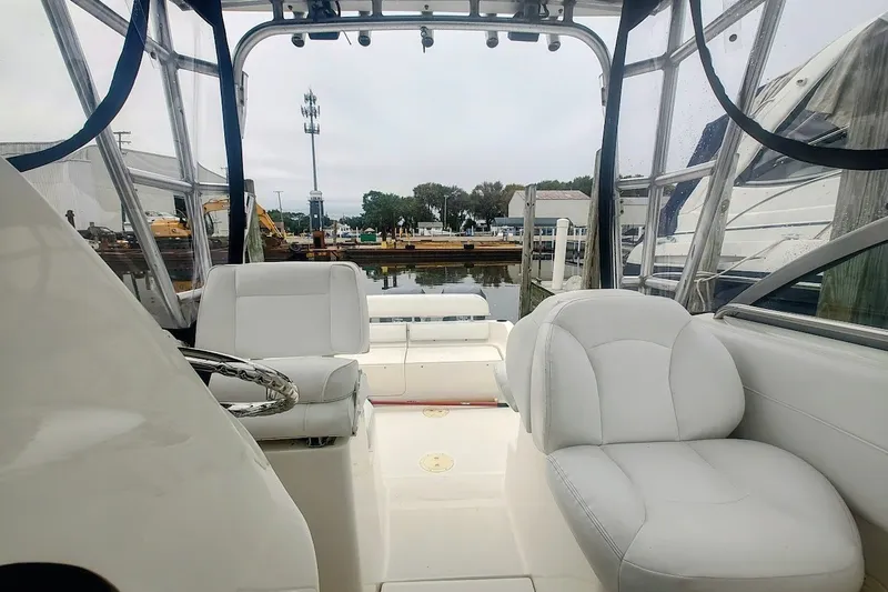 Slide: The Image of 2005 Robalo R265 Walkaround boat interior with white seating and marina view. - 14
