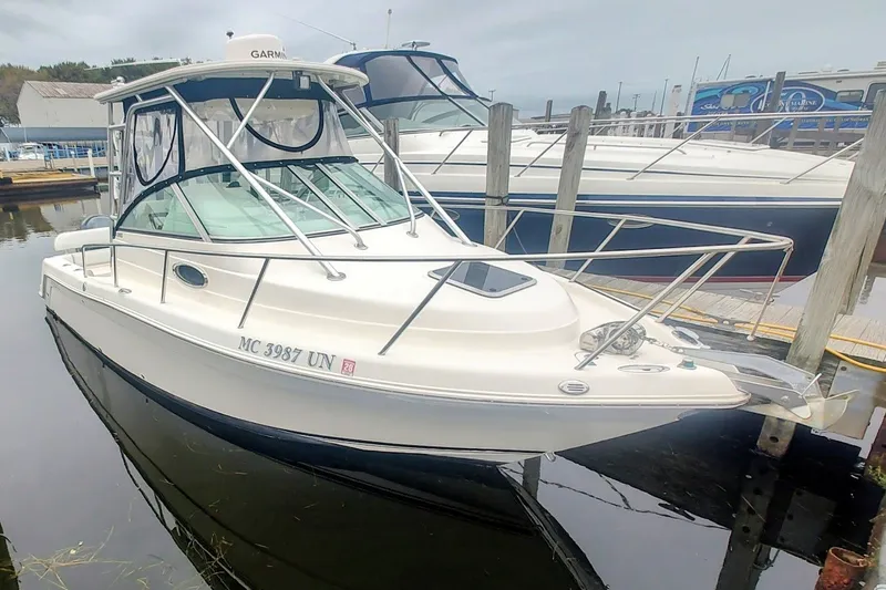 The Image of 2005 Robalo R265 Walkaround boat docked in a marina, featuring a sleek design and enclosed cabin. - 0