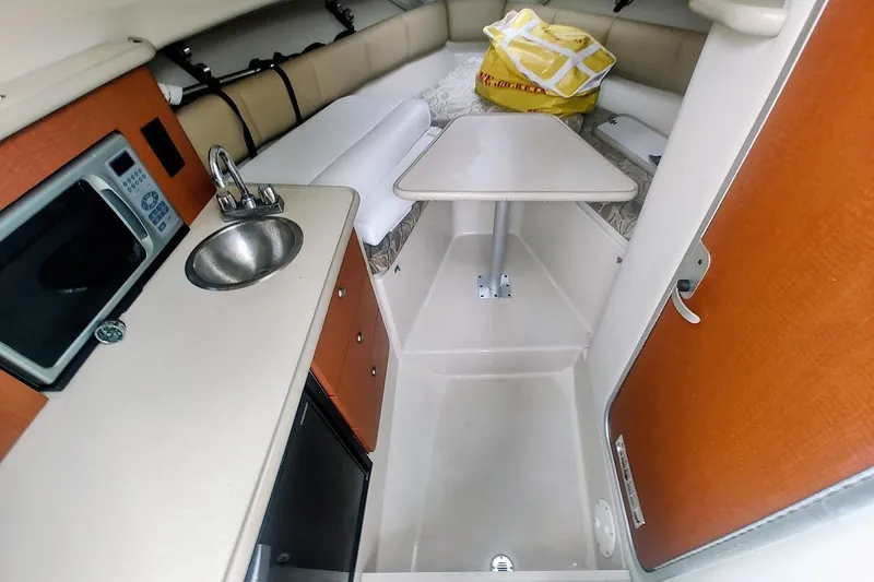 Slide: The Image of 2005 Robalo R265 Walkaround cabin interior with kitchenette, sink, and seating area. - 28
