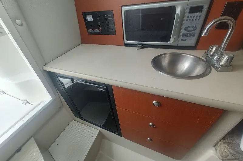 Slide: The Image of 2005 Robalo R265 Walkaround boat interior with microwave, sink, and storage drawers. - 26