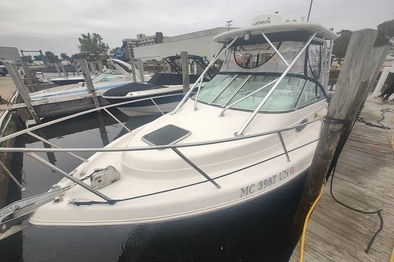 Slide: The Image of 2005 Robalo R265 Walkaround boat docked at a marina, featuring a sleek white design. - 1