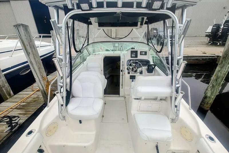 Slide: The Image of 2005 Robalo R265 Walkaround boat interior with white seating and control panel at dock. - 8