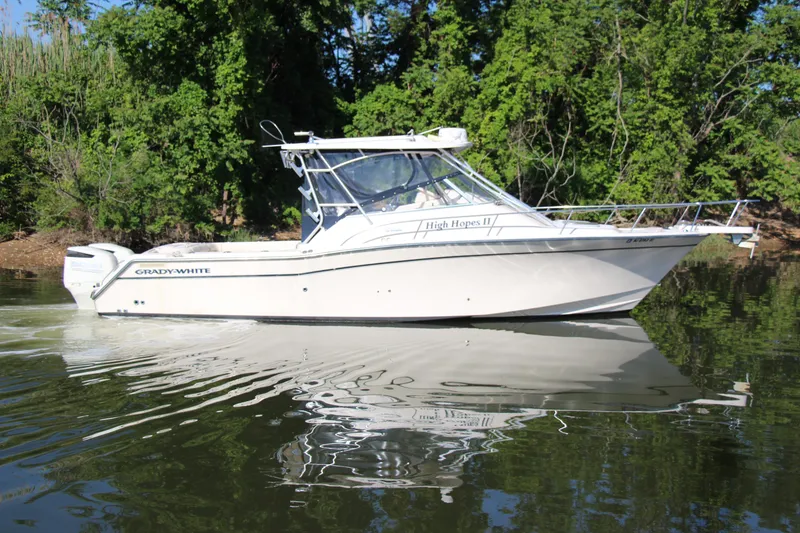 Slide: The Image of 2005 Grady-White Express 330 boat on calm water, surrounded by lush greenery. - 1